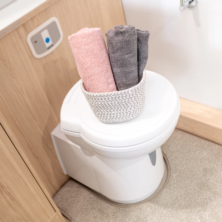 Image of the toilet and a basket of towels, inside the Whirlwind 520 model by Elddis.