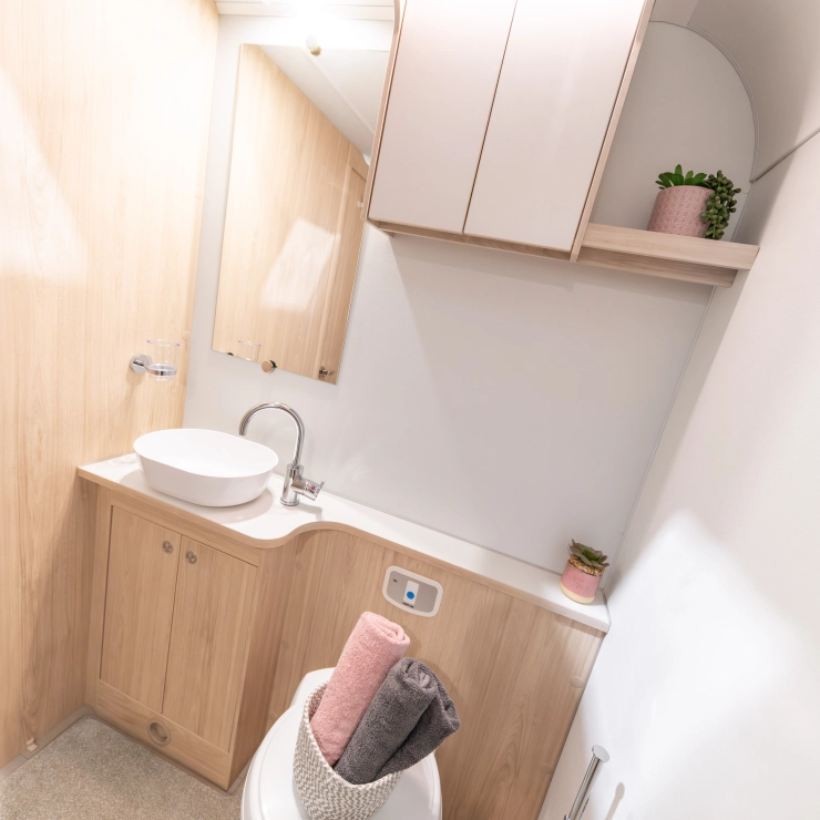 Another angle of the rear bathroom inside the Elddis Whirlwind 520 caravan. It shows the sink, toilet, cupboard and a large mirror at one end of the bathroom.
