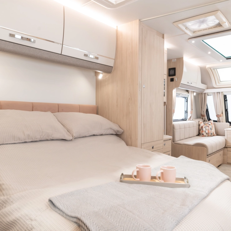 The bedroom inside the Whirlwind 554. Showcasing the transverse rear island bed looking through into the lounge seating area.